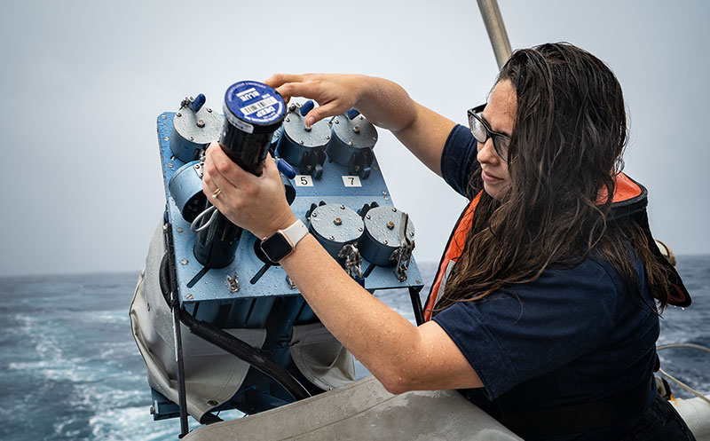 Shannon replenishes the expendable bathythermographs (XBTs) in the XBT auto-launcher. The XBTs collect temperature data about the water column and, when combined with historical salinity profiles from the World Ocean Atlas, allow the mapping team to generate sound velocity profiles that are applied to the multibeam mapping data. The XBT auto-launcher was designed by the NOAA Atlantic Oceanographic and Meteorological Laboratory and enables remote launches of XBTs by personnel on the ship or on shore.